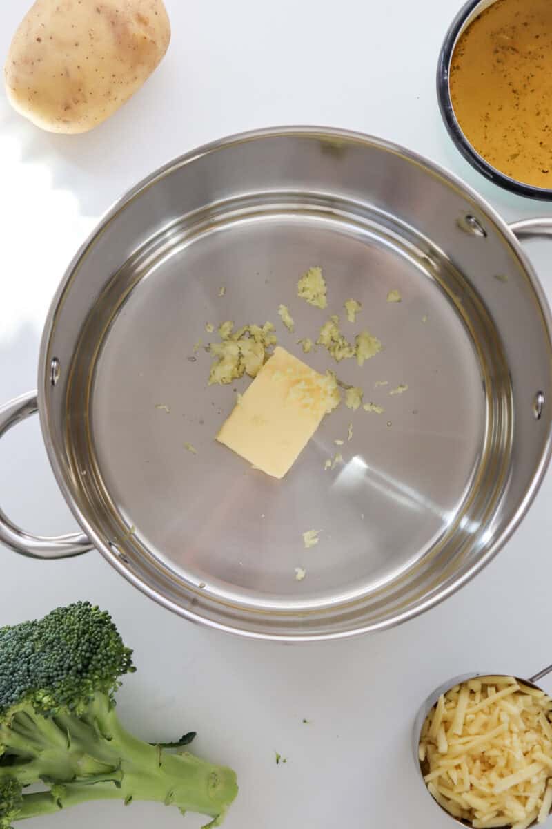 An overhead image of butter and minced garlic in a large pot.