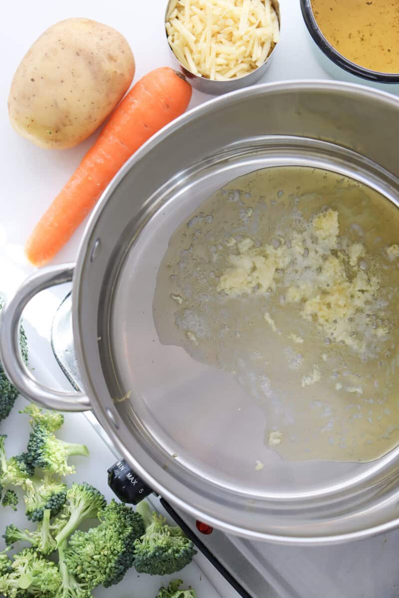 An overhead image of butter and minced garlic in a large pot with the other ingredietns lying on the table.