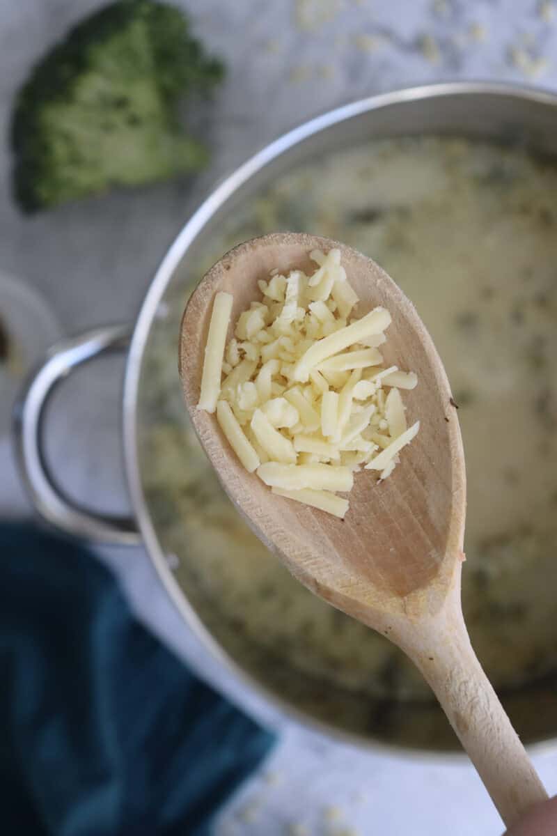 Close-up image of shredded cheddar in a wooden laddle.