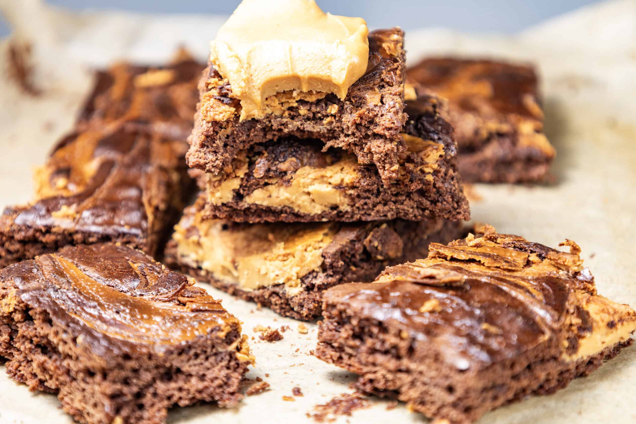 Close-up image of a batch of peanut butter brownies with a stack of three in the middle, the top one bitten.