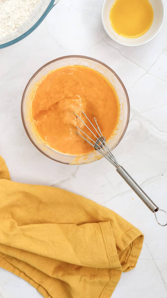 Overhead image of pumpkin pancake batter in a bowl with a whisk.