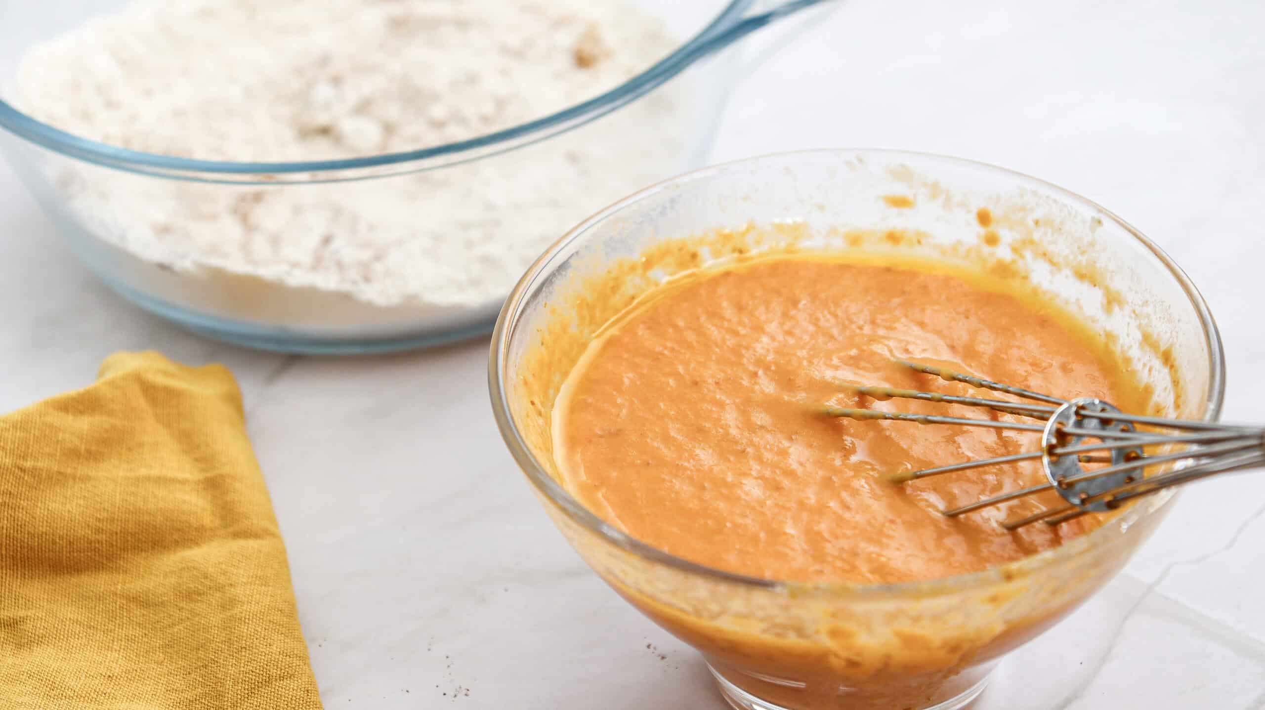 Close-up image of pumpkin pancake batter in a bowl with a whisk.