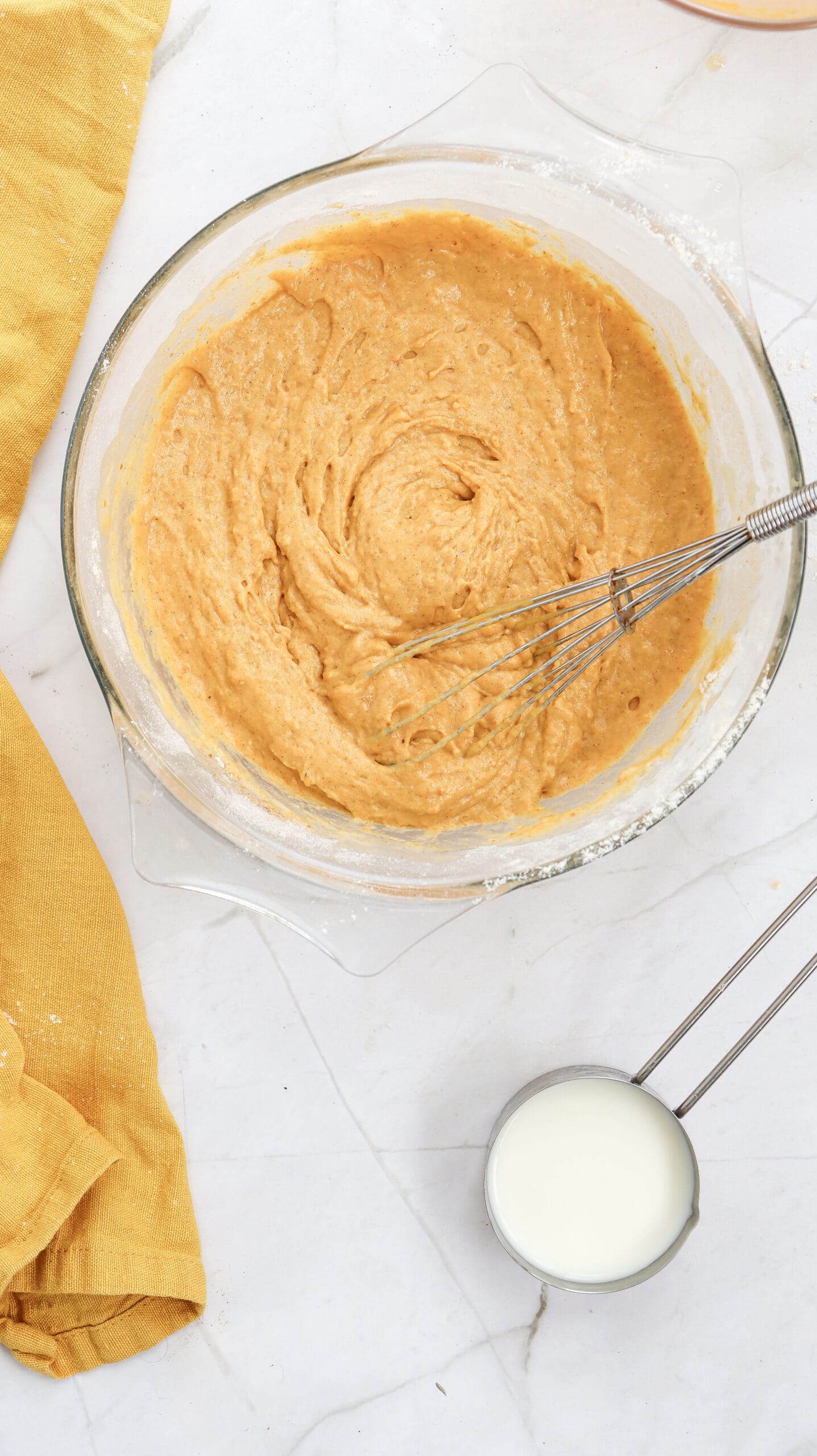 Overhead image of pumpkin pancake batter in a bowl with a whisk.