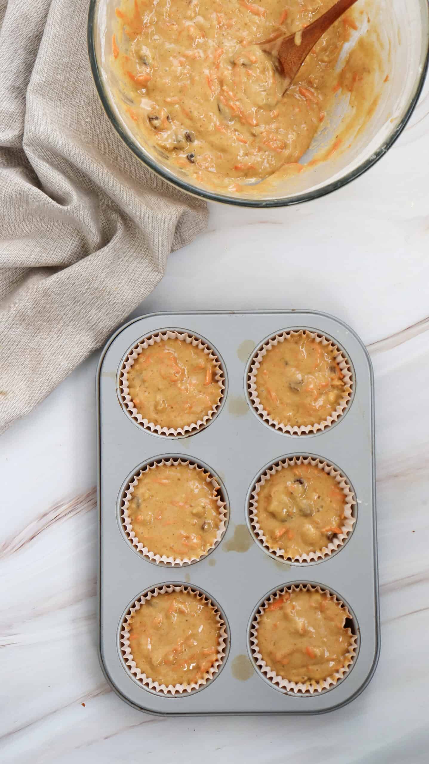 Overhead image of carrot cake muffins batter in a mixiing bowl and baking sheet.