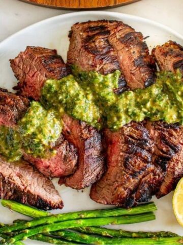 Overhead image of sliced italian steak with sauce on a plate.