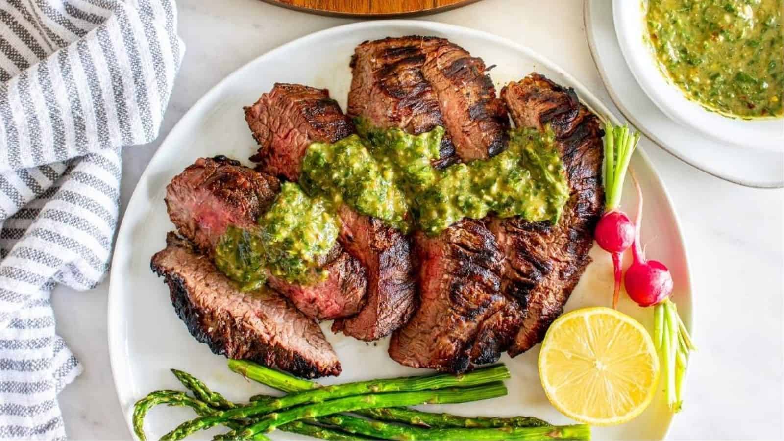 Overhead image of sliced italian steak with sauce on a plate.