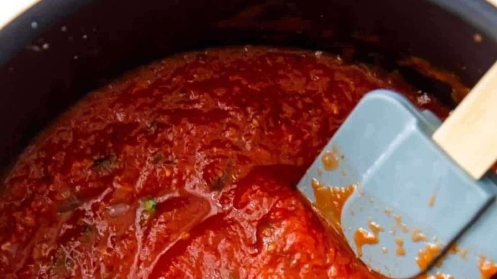 Low Carb Spaghetti Sauce in a black pot with basil and a spatula.