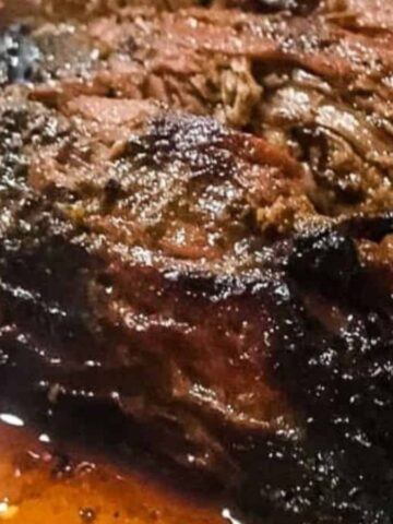 A cooked steak on a cutting board being sliced with beef juices.