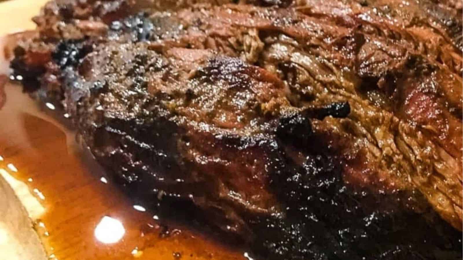 A cooked steak on a cutting board being sliced with beef juices.