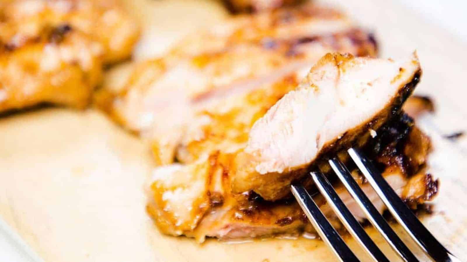A slice of miso chicken on a fork with more slices in the background.