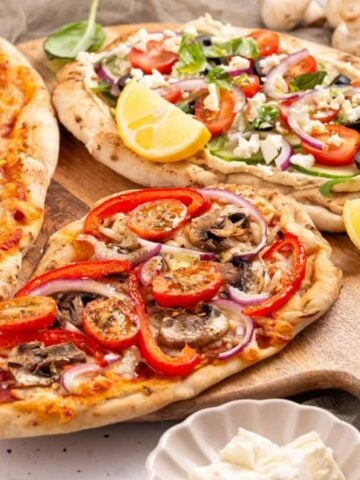 An image of naan pizza with different toppings on each.
