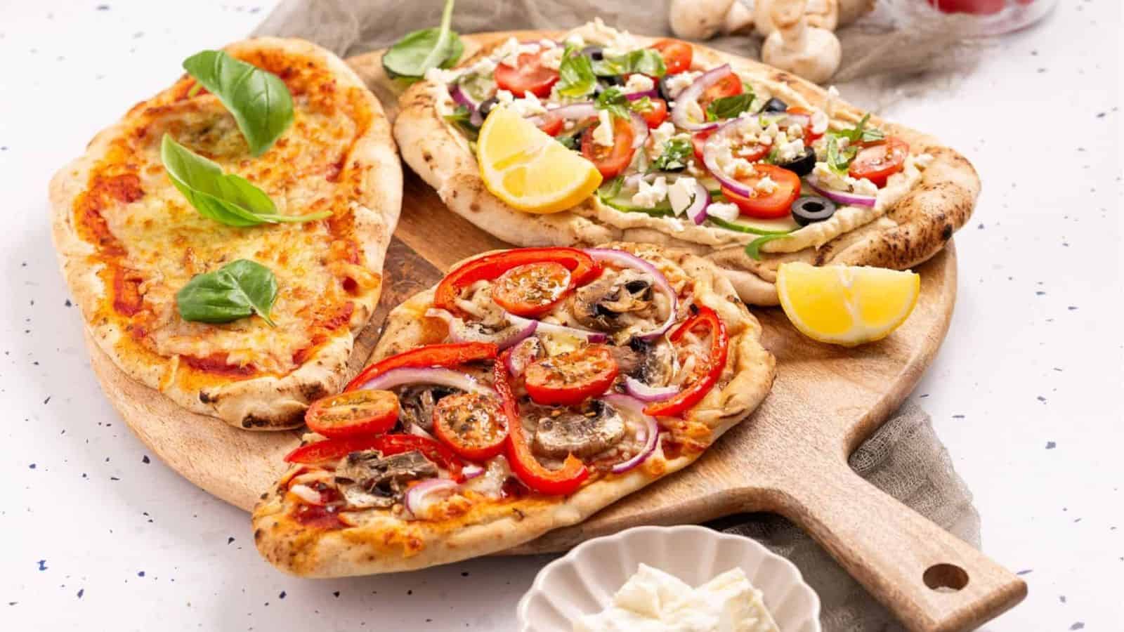 An image of naan pizza with different toppings on each.