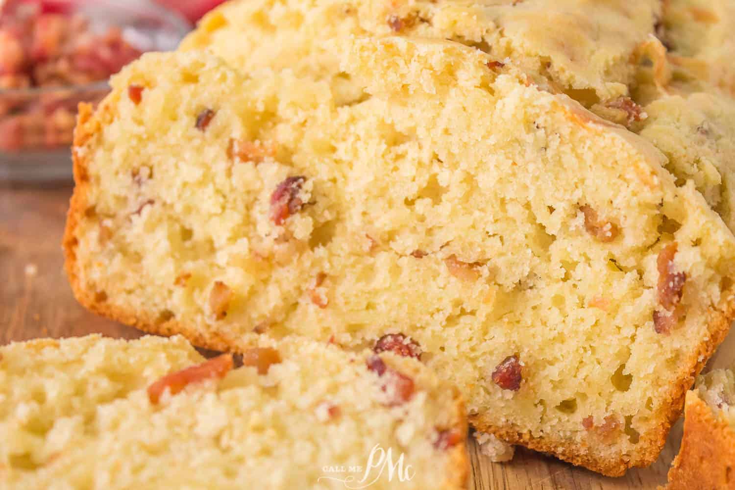 A quick bread loaf with bacon on a cutting board.