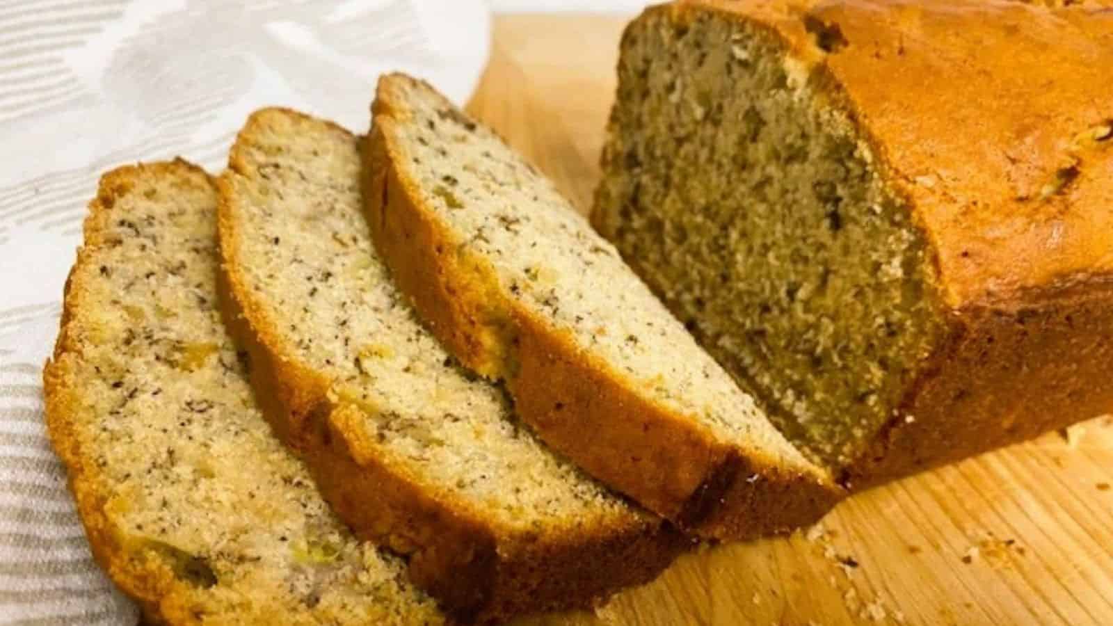 Sliced loaf of banana bread on wooden board.