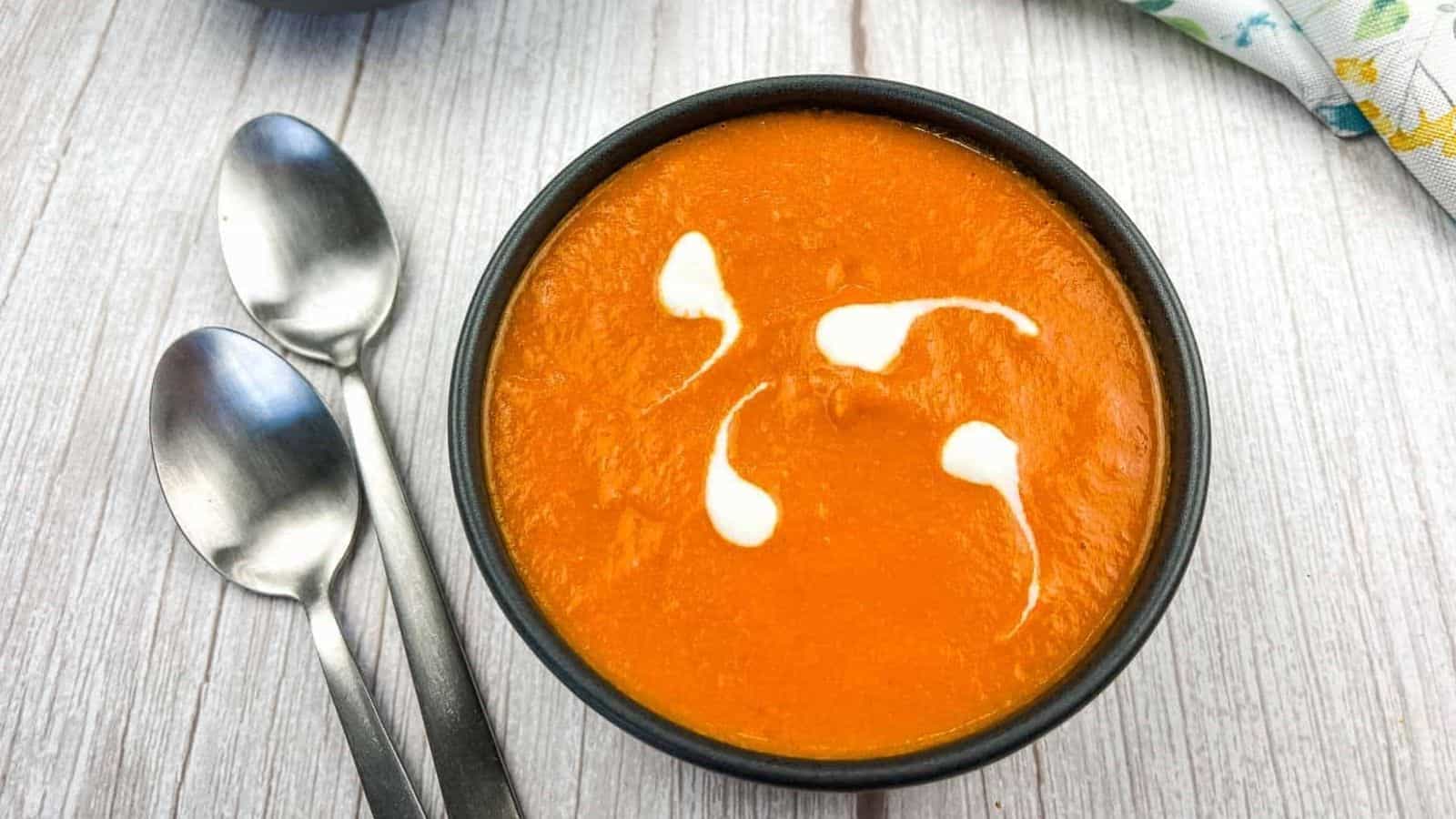 A bowl of oven-roasted tomato soup with two spoons.