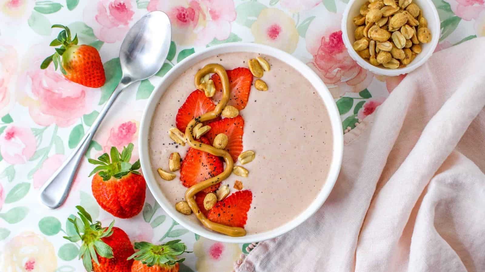 Smoothie  topped with strawberries, peanuts, and peanut butter swirl in bowl.