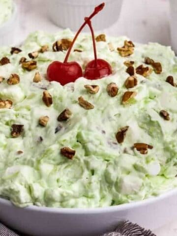 Pistachio salad topped with nuts and cherries.