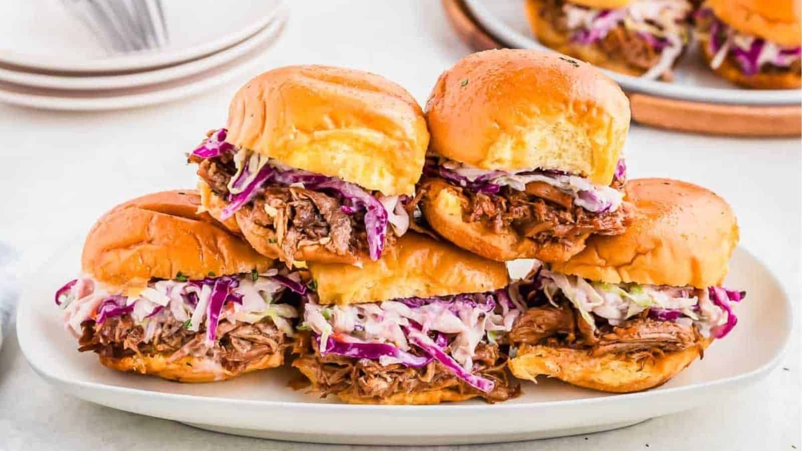 A stack of pulled pork sliiders on a dish.