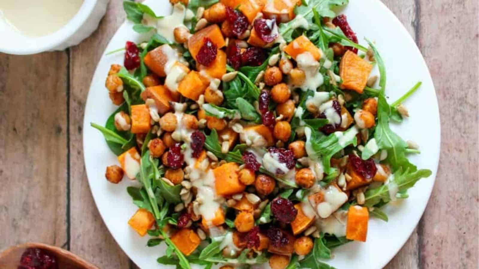 Top view of roasted sweet potato and chickpea salad with tahini sauce on a plate.