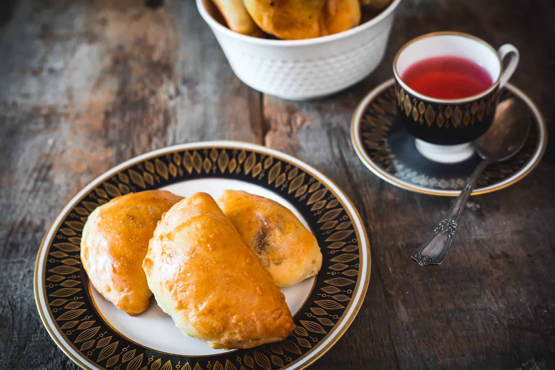 Three piroshki on a plate with tea.