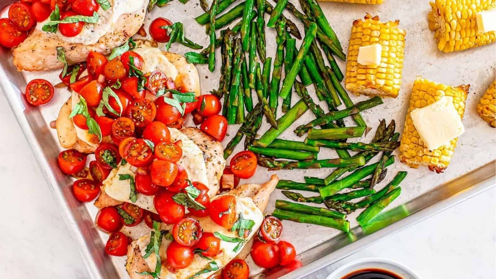 Overhead image of sheet pan chicken caprese and vegetables.