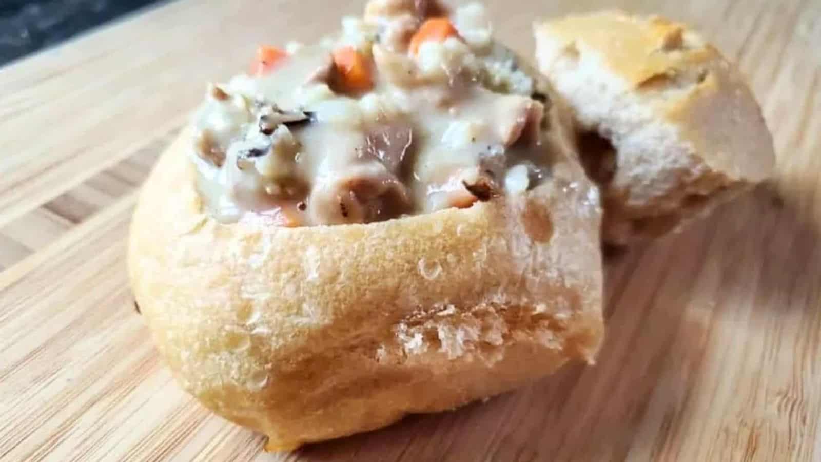 Image shows a closeup of a Sourdough Bread Bowl filled with chicken and wild rice soup.