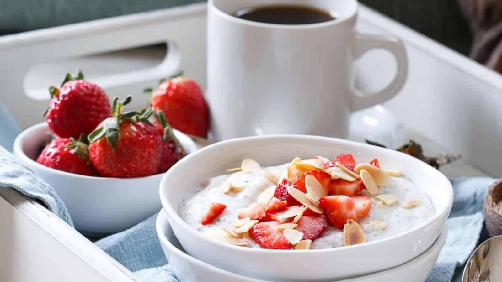 Strawberry coconut polenta breakfast bowl with straberries and a cup of coffee in a tray.