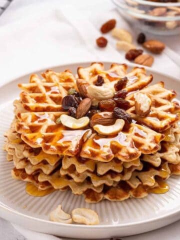 An image of a stack of sweet potato waffles with cashews and dried fruits on top.