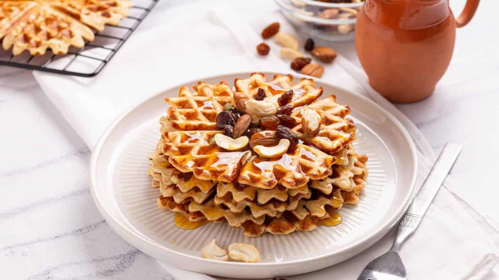 An image of a stack of sweet potato waffles with cashews and dried fruits on top.