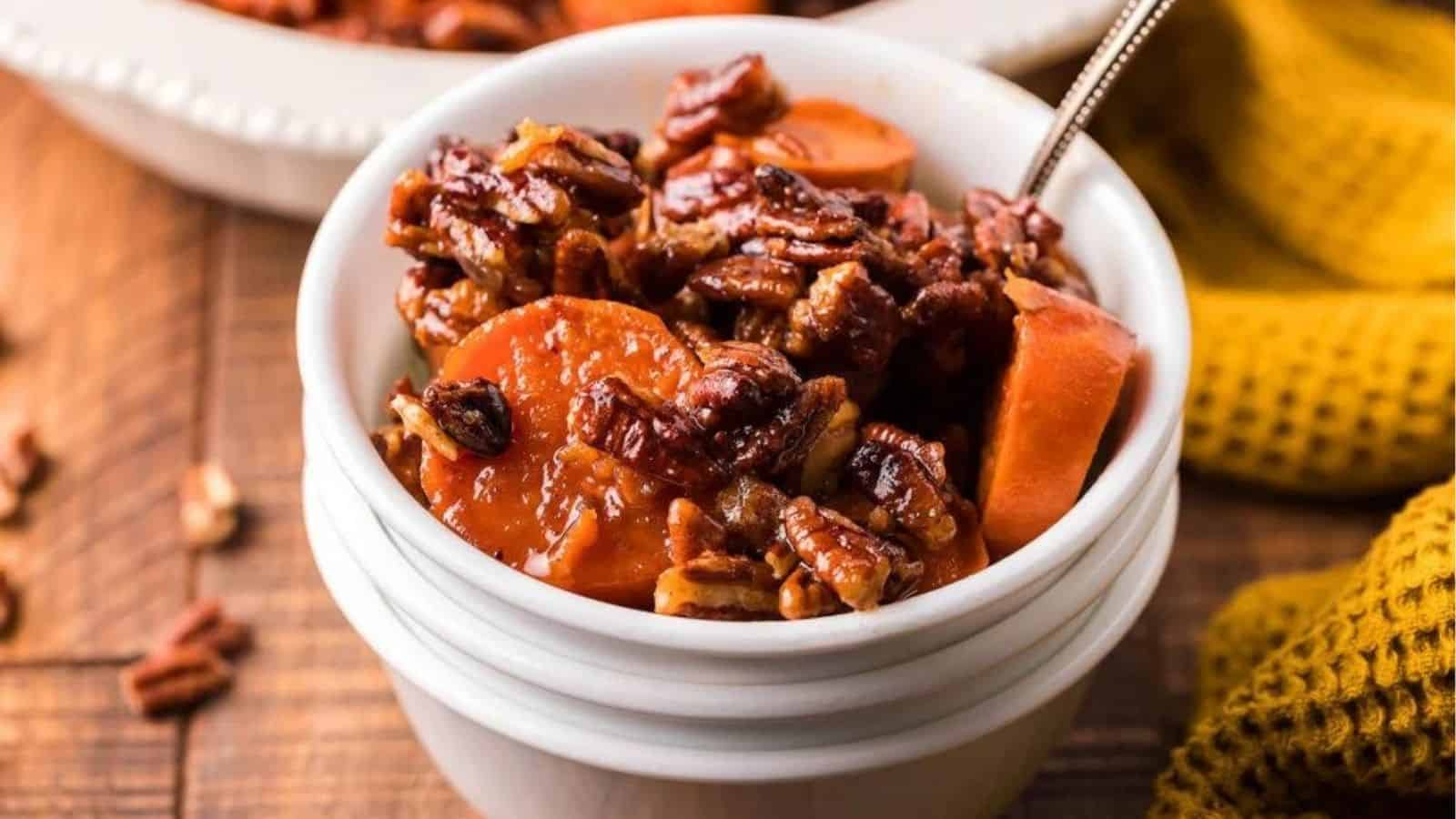 Close-up image of sweet potatoes with candied pecans in a small bowl.