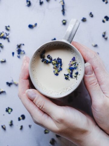 Someone holding a mug of Sweet Violet Moon Milk.