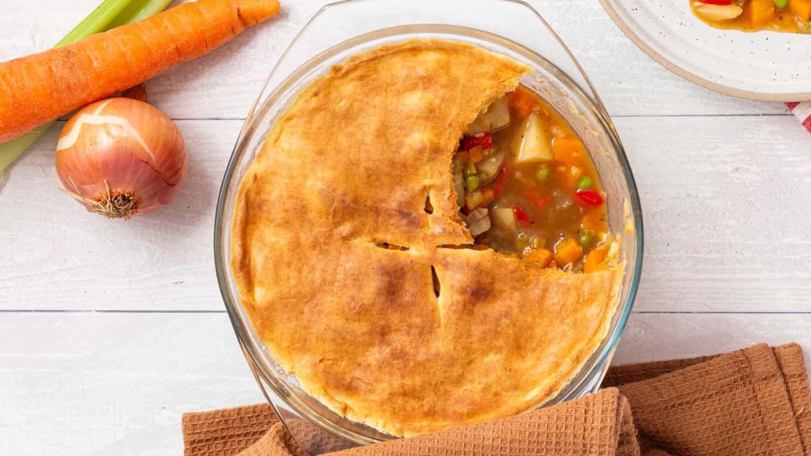 An image of vegetable pot pie in a baking dish, with a portion missing.