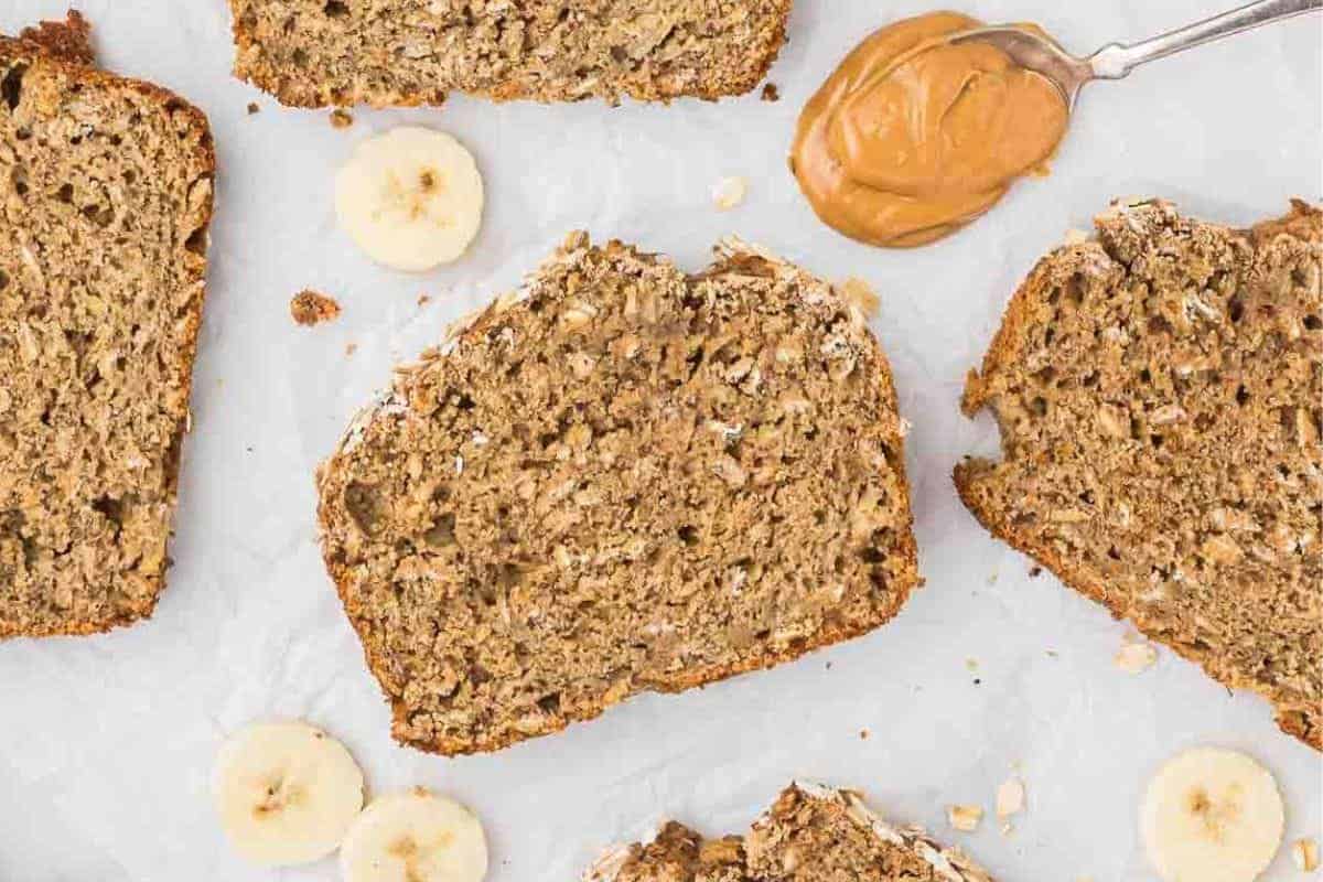 Slices of oatmeal banana bread with a spoonful of peanut butter beside them.