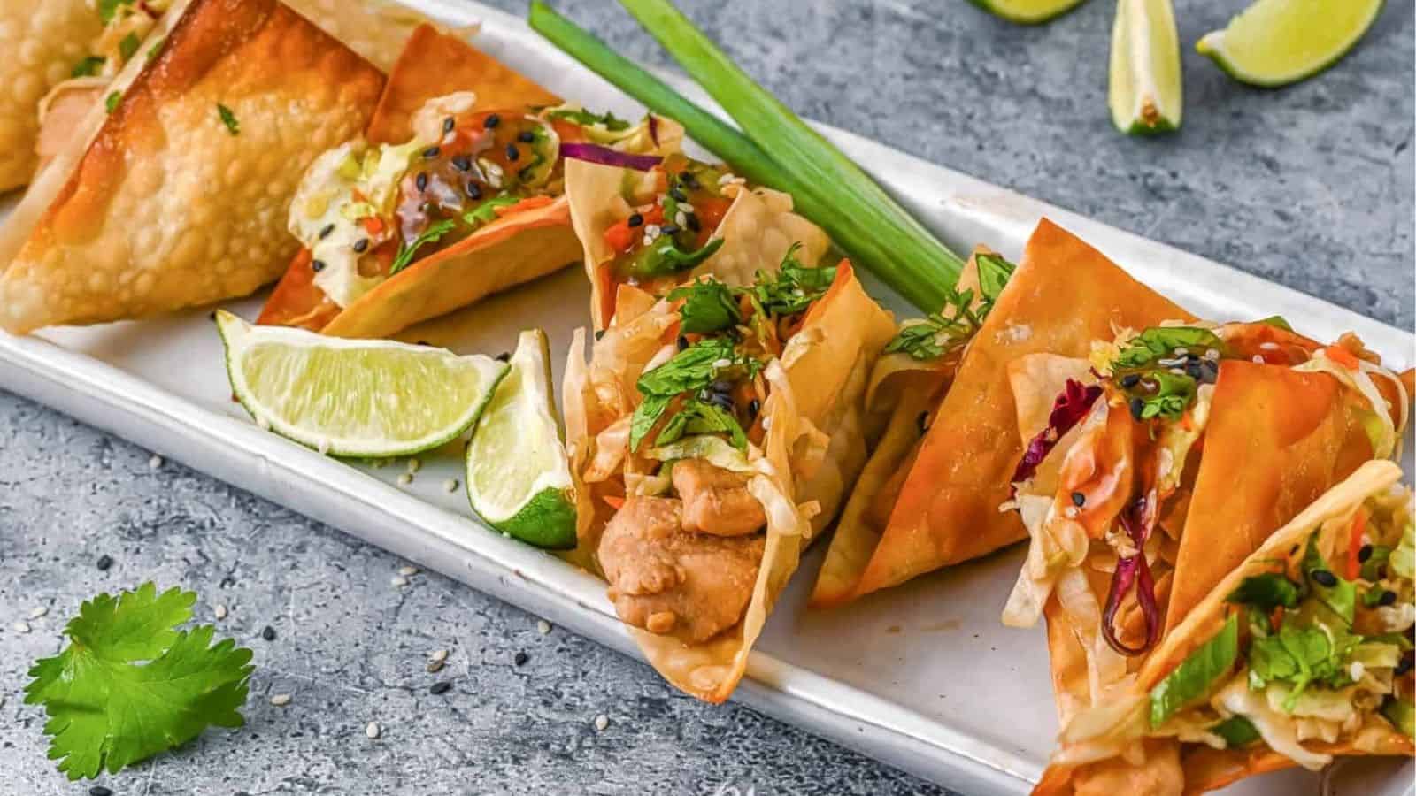 Long tray lined with wonton tacos and lime wedges.