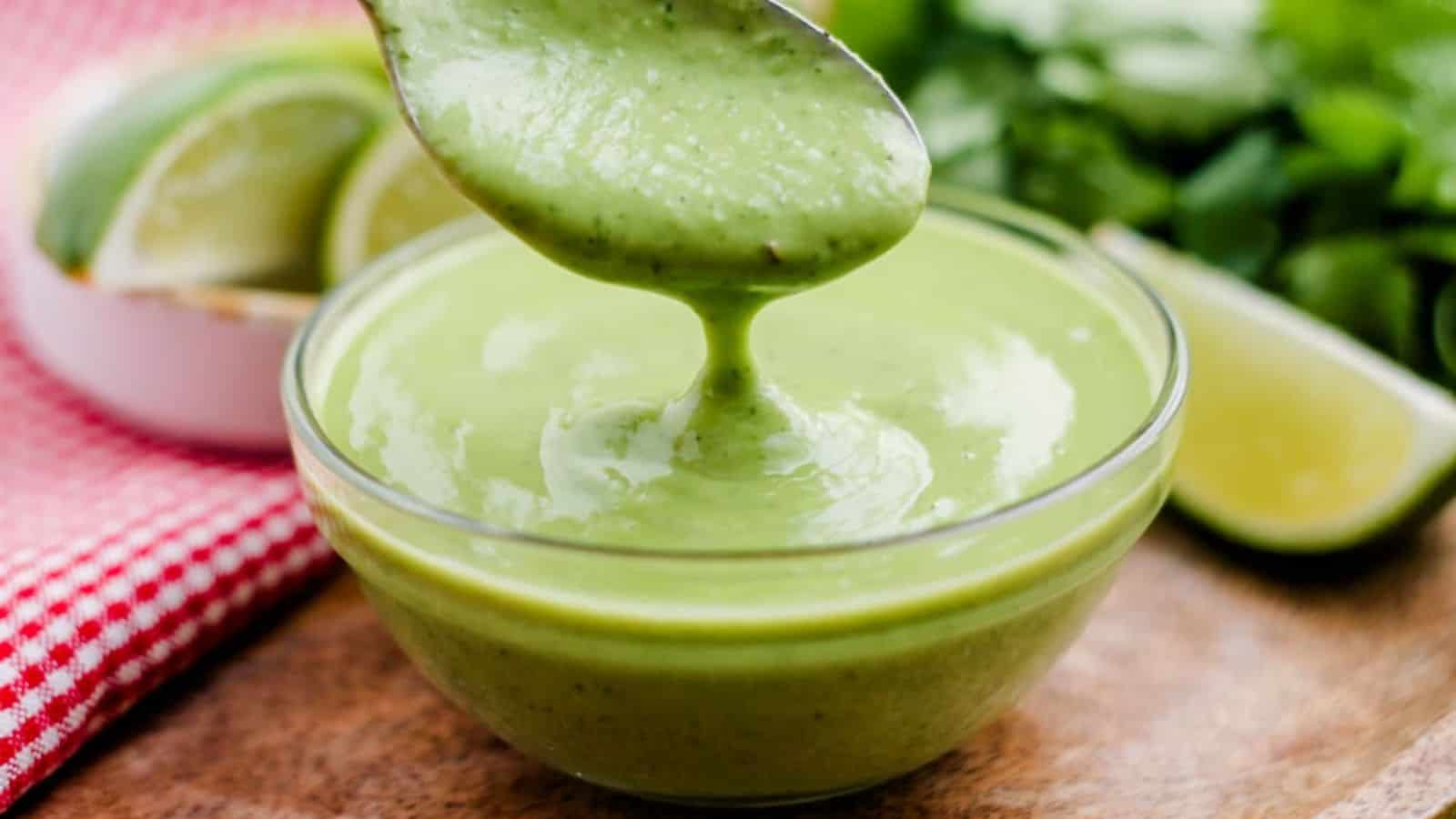 Avocado cilantro dressing being poured into a small dish.
