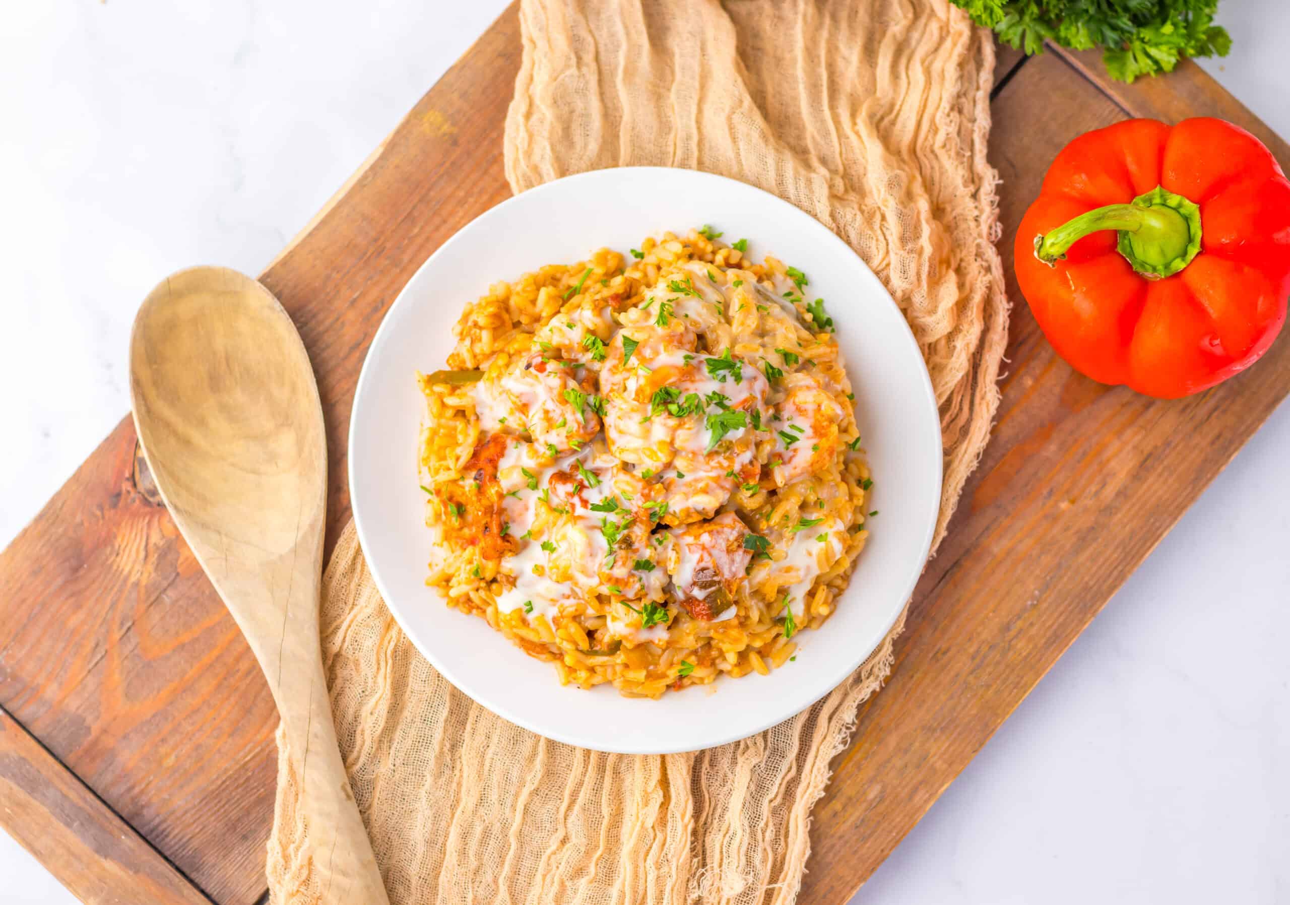 Overhead image of Chicken and Queso Rice Bake garnished with fresh chopped parsley on a plate.
