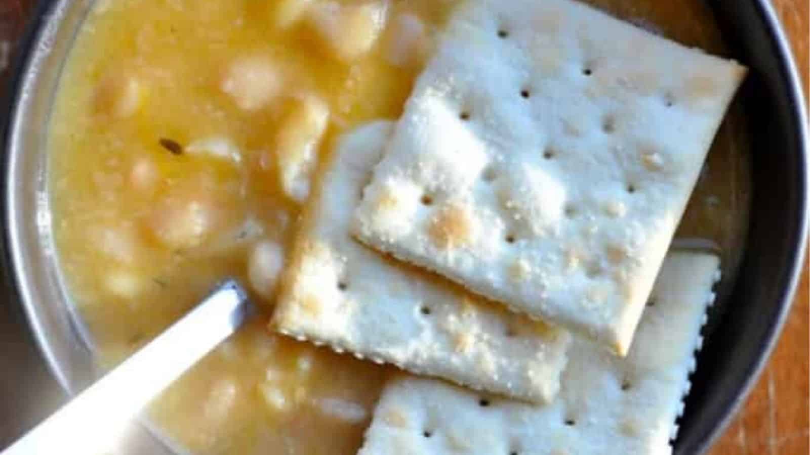 Top view of slow cooker bean with bacon topped with crackers in a bowl.