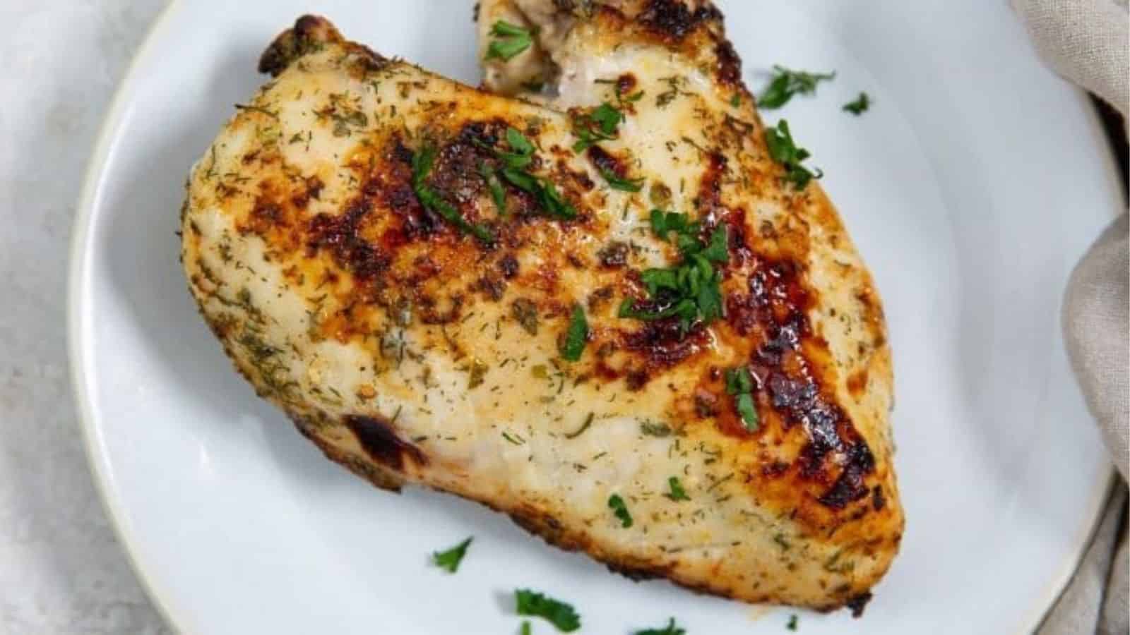 Easy Air Fryer Ranch Chcken Breast on a white plate with parsley and a fork.