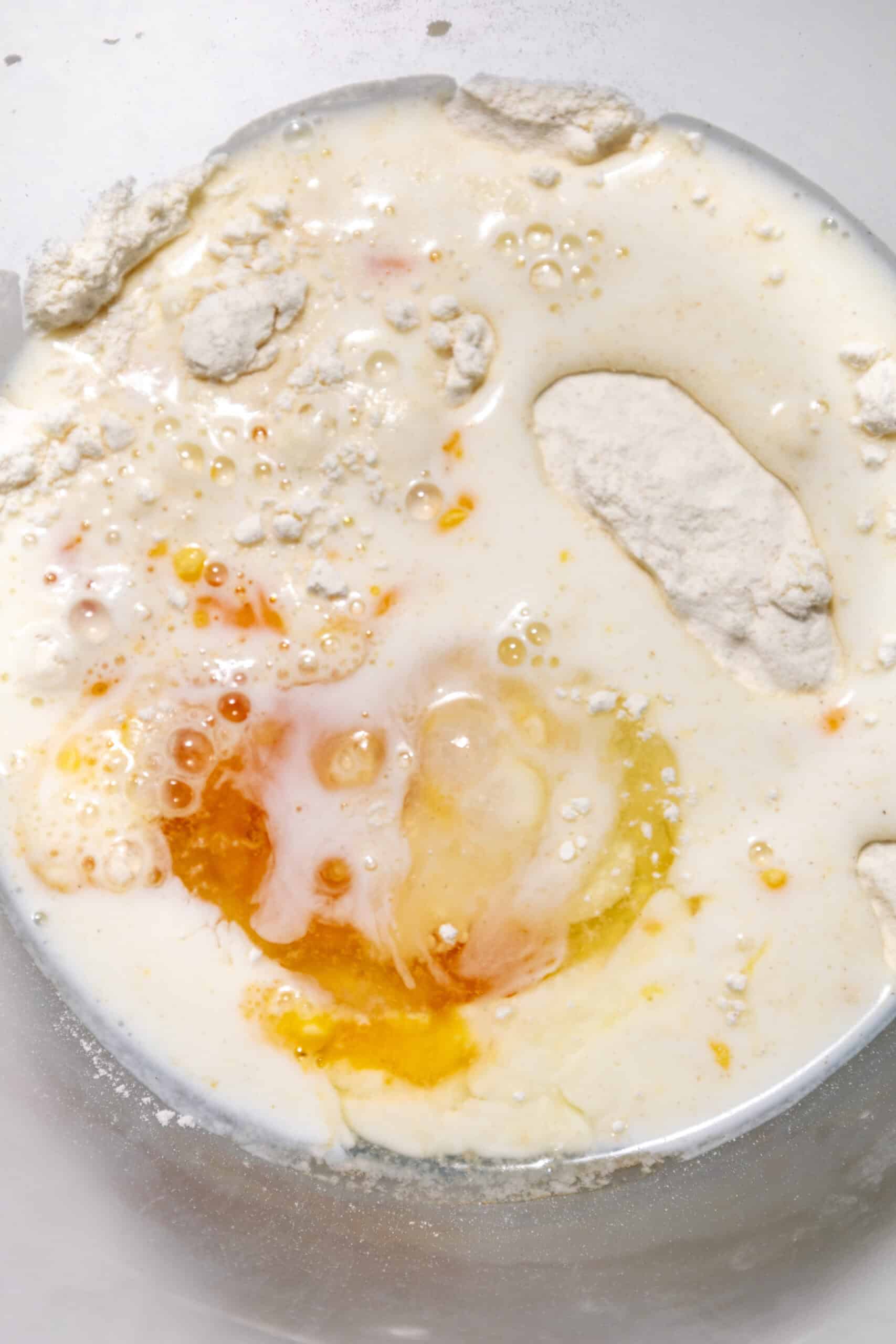 Close-up image of wet ingredients being added to dry ingredients in a mixing bowl.