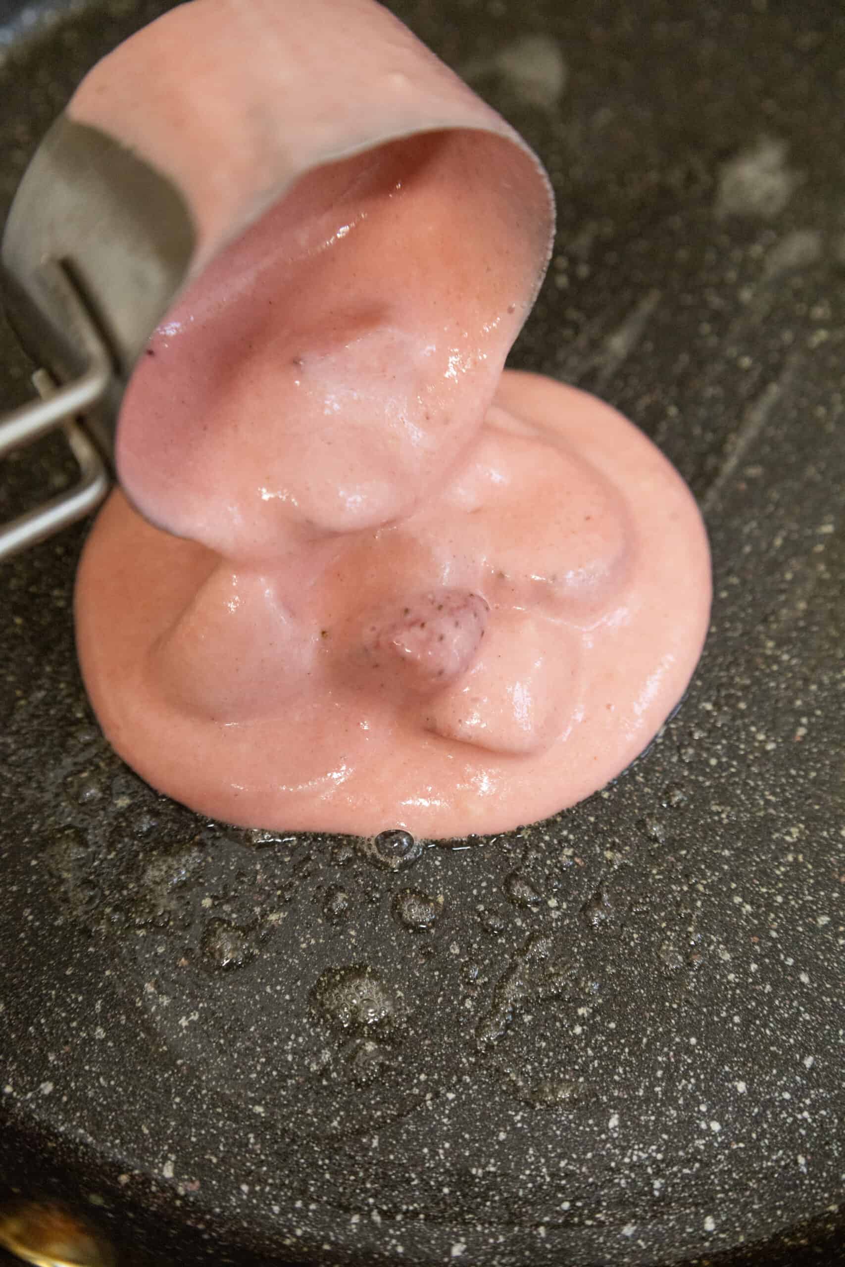 Close-up image of Strawberry Delight Pancakes mixture being poured into a skillet.