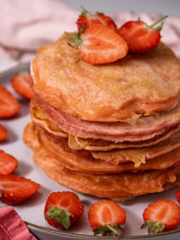 Close-up image of a stack of Strawberry Delight Pancakes topped with sliced strawberries.