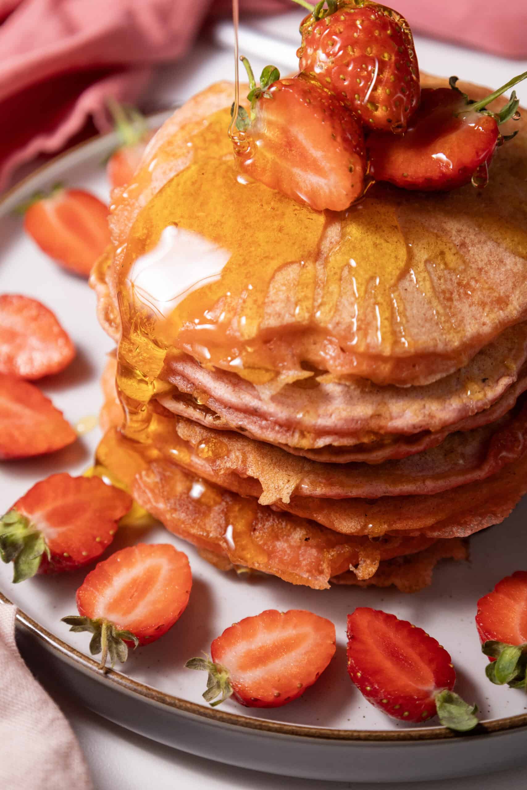 Close-up image of a stack of Strawberry Delight Pancakes topped with sliced strawberries.