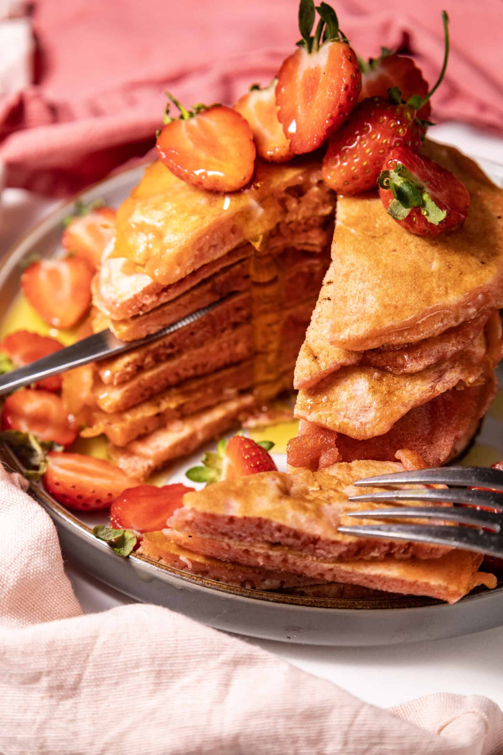 Close-up image of a stack of Strawberry Delight Pancakes topped with sliced strawberries.