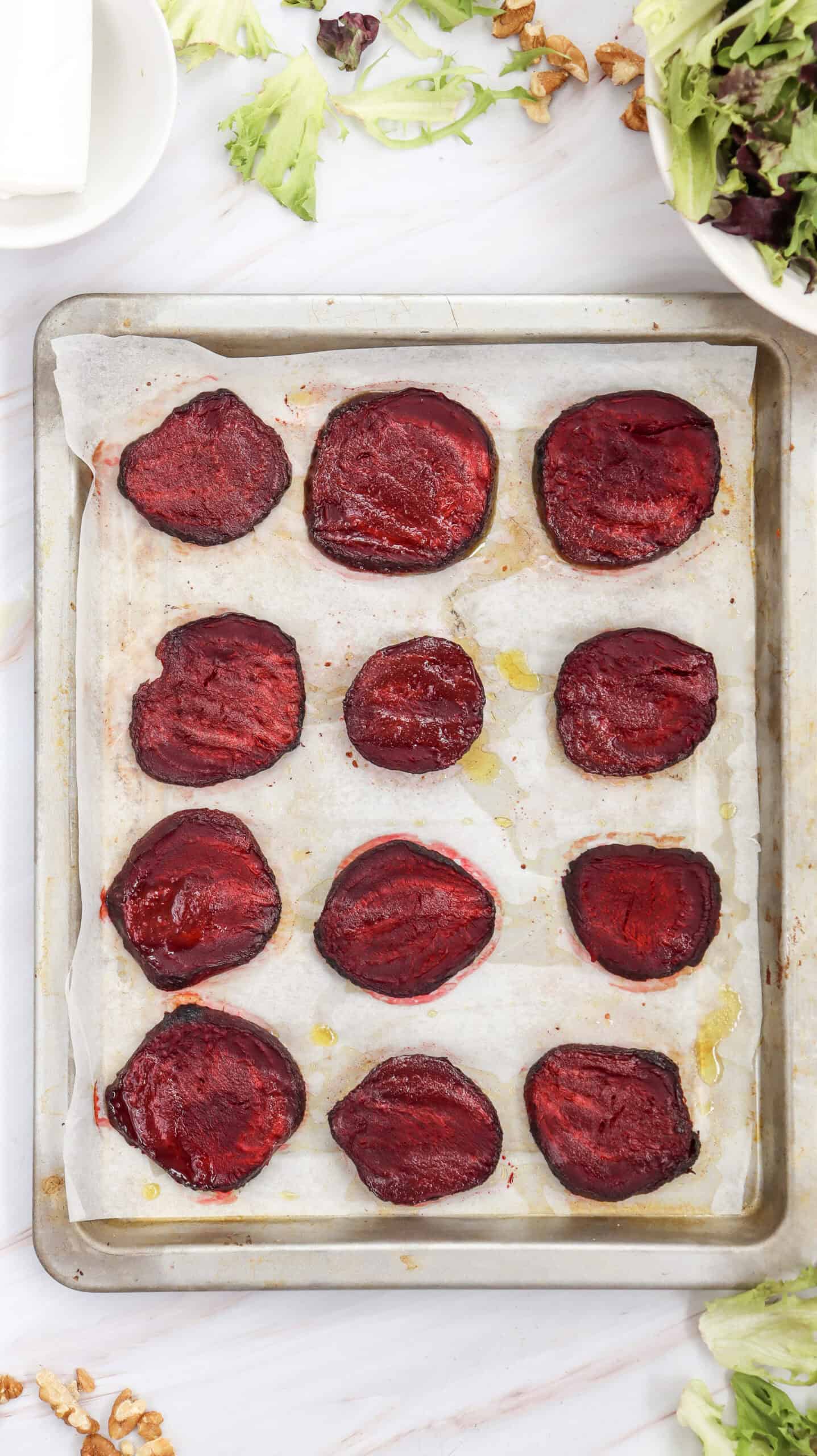 Overhead image of roasted beetroot slices arranged on a sheet pan.