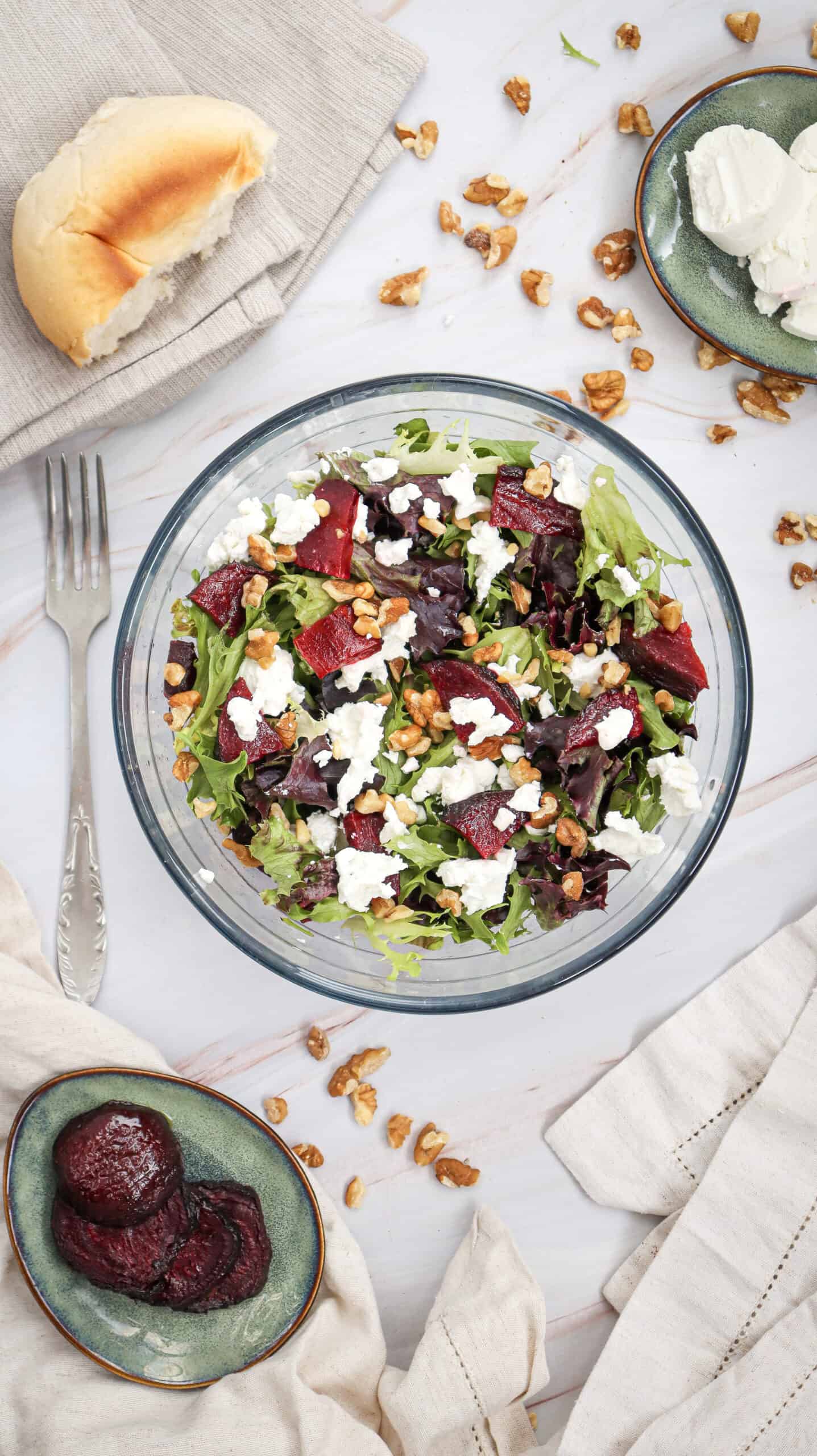 Overhead view of Grilled Beetroot Goat Cheese Salad in a bowl, with roasted beetroot slices, chopped walnuts, and goat cheese in the background.