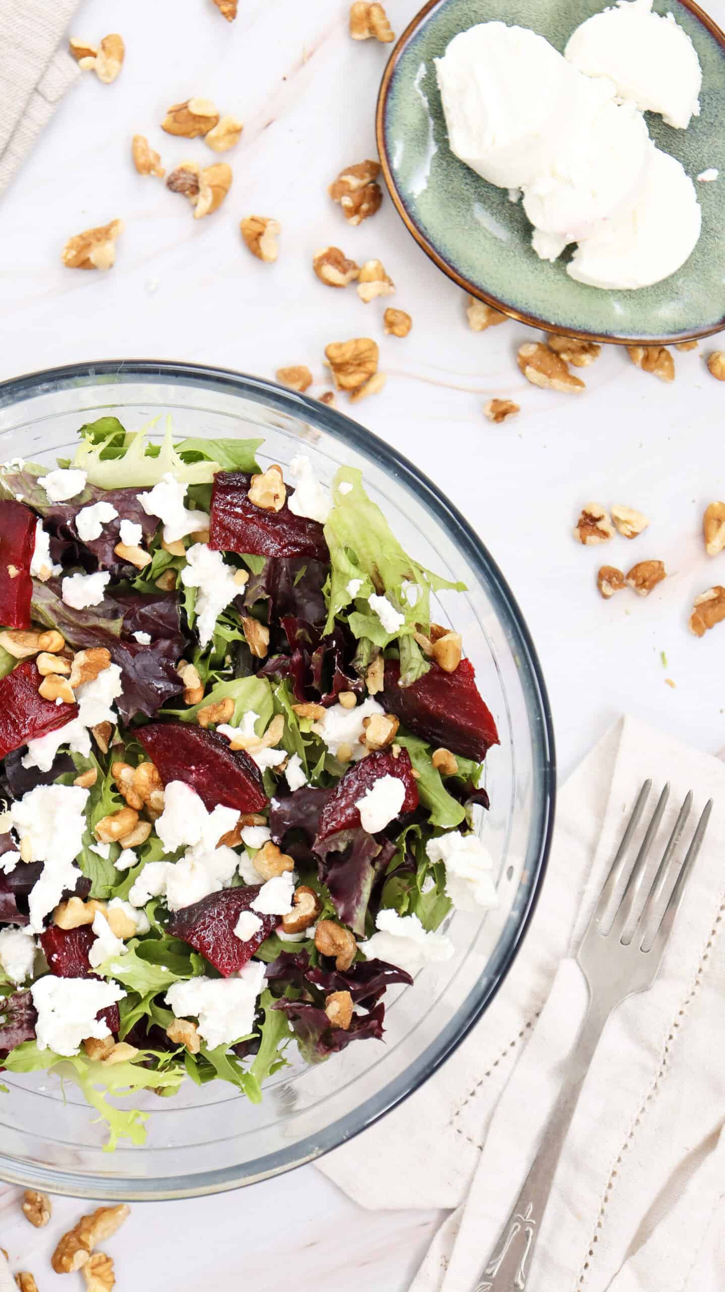 Overhead image of Grilled Beetroot Goat Cheese Salad in a bowl, with goat cheese and chopped walnuts visible in the background.