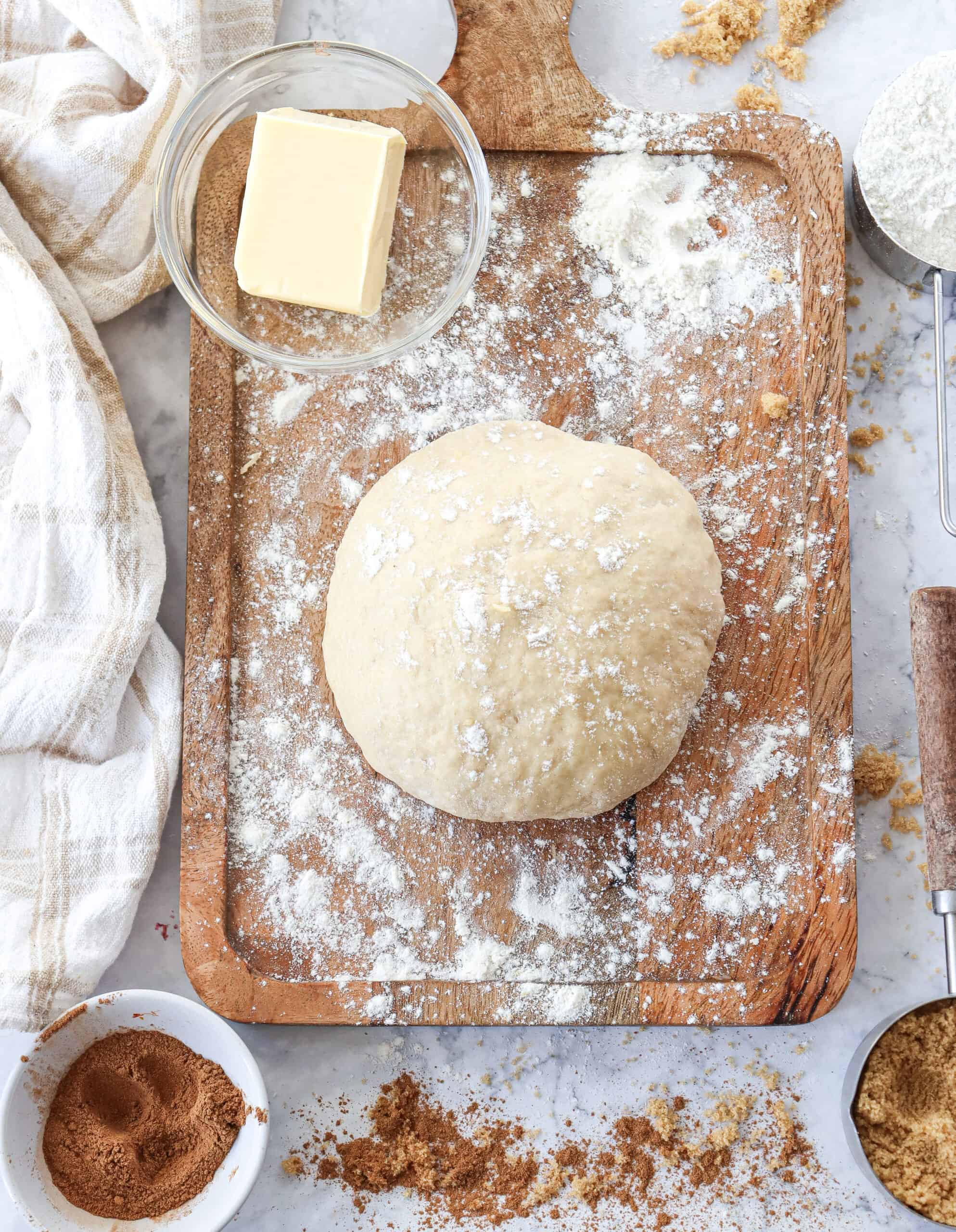 Overhead view of dough with butter on a flour-dusted chopping board.