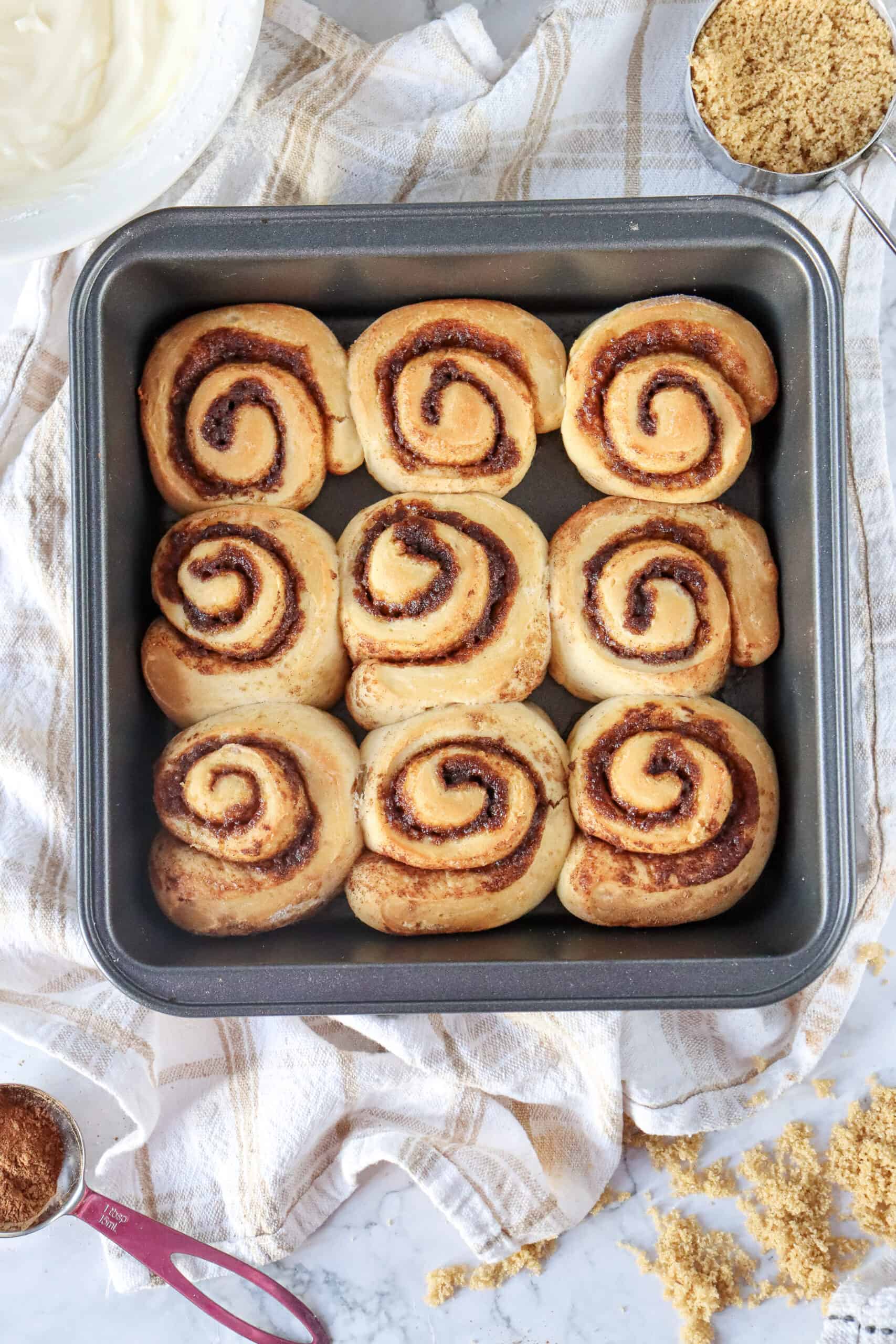 Golden-brown cinnamon rolls fresh from the oven, slightly puffed and soft.