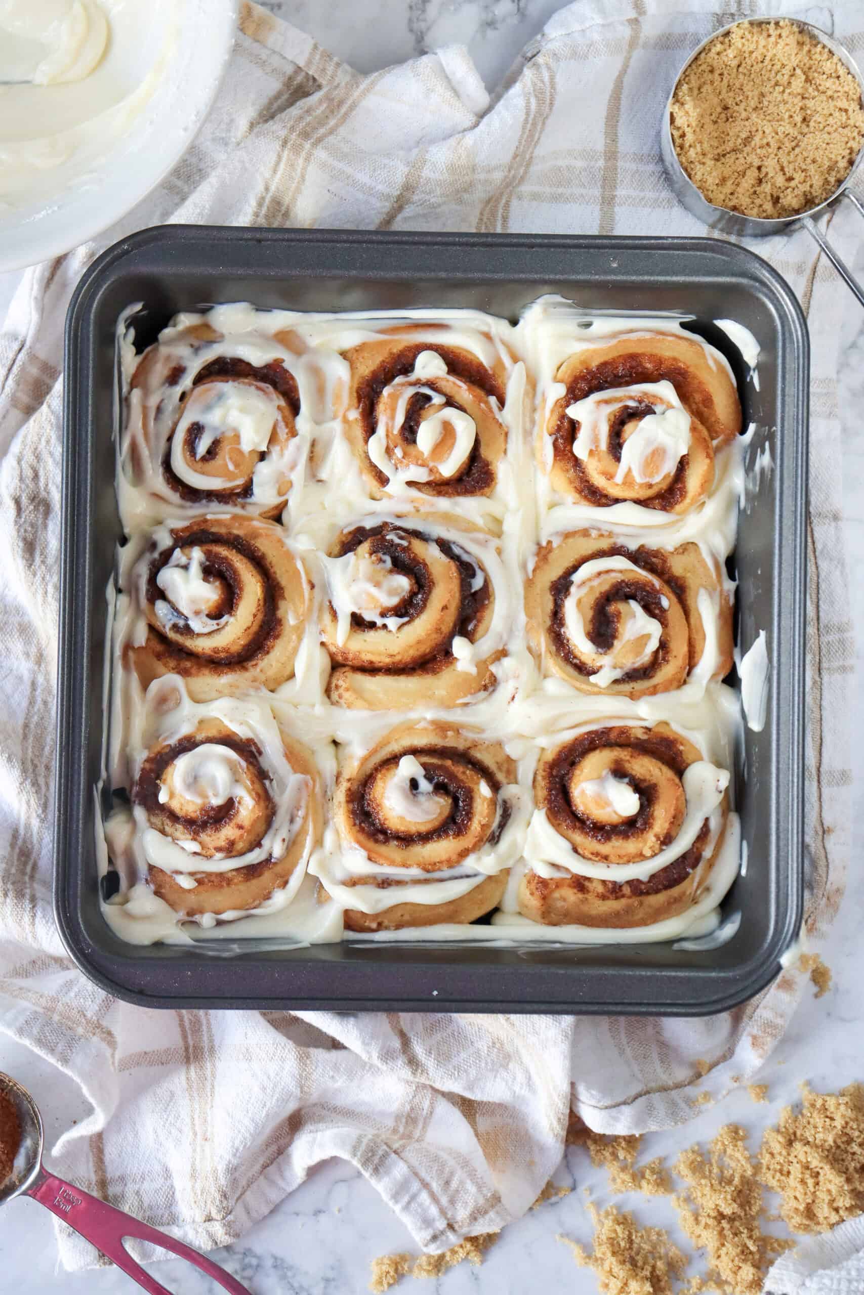 Glazed cinnamon rolls in a square pan.