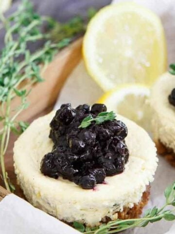 Three Lemon Thyme Blueberry Mini Cheesecakes on a wooden crate.
